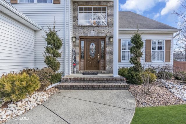 entrance to property featuring roof with shingles