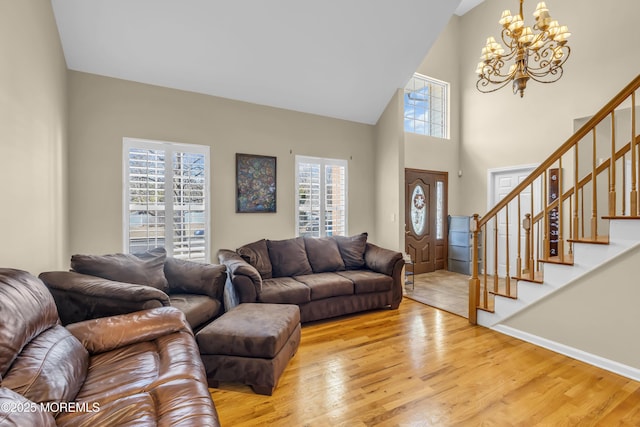 living area featuring wood finished floors, a towering ceiling, baseboards, stairway, and an inviting chandelier