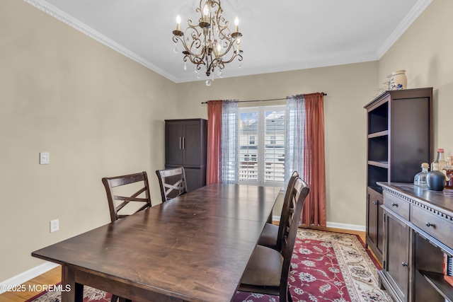 dining area with light wood-style floors, a notable chandelier, baseboards, and crown molding