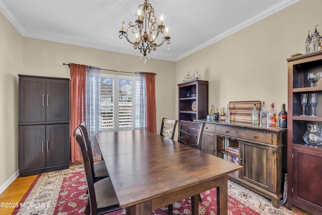 dining room with light wood-style floors, baseboards, ornamental molding, and a chandelier