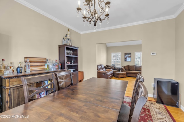 dining space with crown molding, baseboards, a chandelier, and wood finished floors