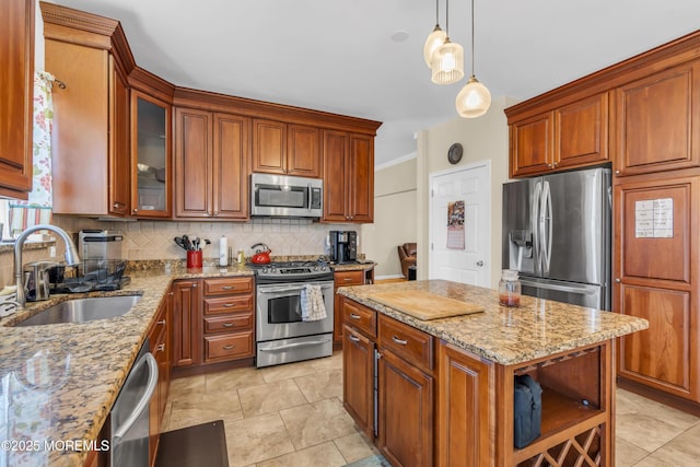 kitchen featuring a sink, appliances with stainless steel finishes, decorative backsplash, light stone countertops, and pendant lighting