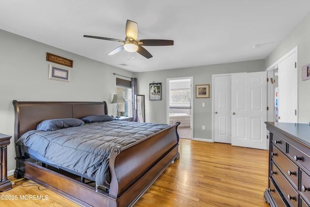 bedroom featuring a ceiling fan, ensuite bath, light wood-style flooring, and baseboards