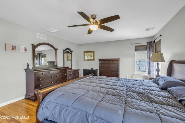 bedroom featuring a ceiling fan, wood finished floors, visible vents, and baseboards