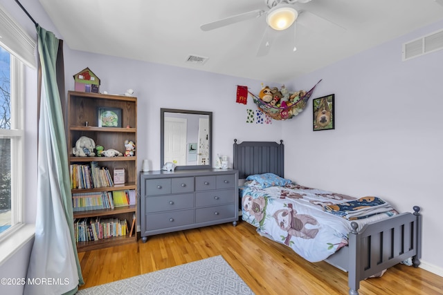 bedroom with ceiling fan, wood finished floors, and visible vents