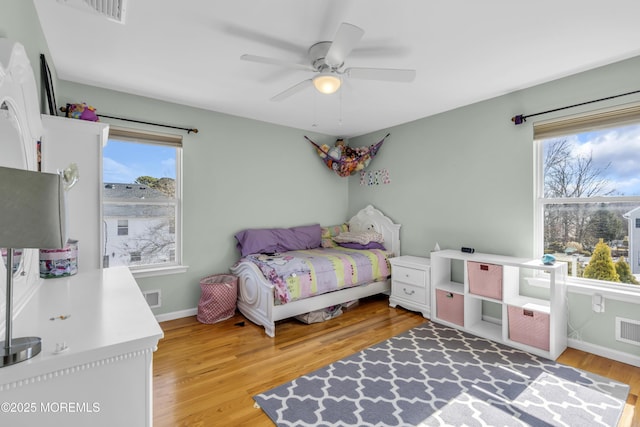 bedroom with light wood finished floors, baseboards, visible vents, and ceiling fan