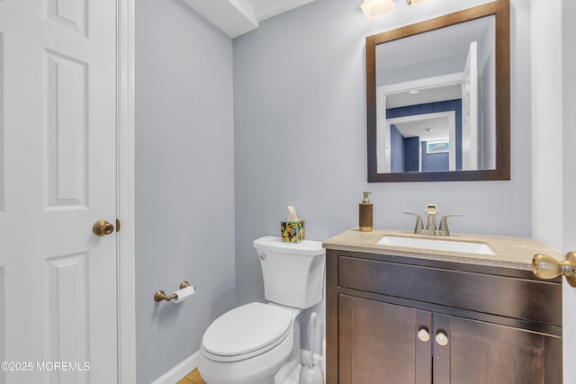 half bath featuring toilet, baseboards, and vanity