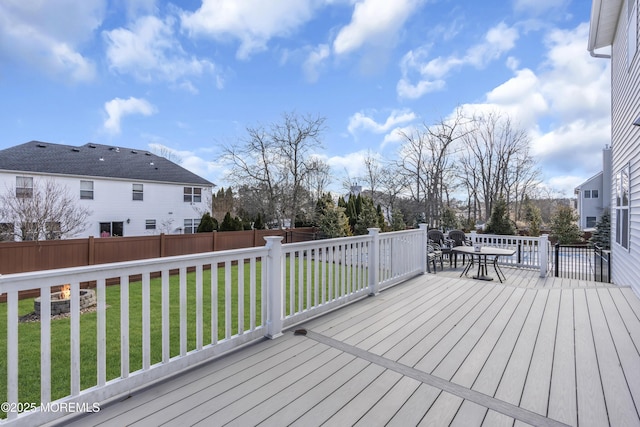 wooden terrace featuring fence, outdoor dining area, and a yard