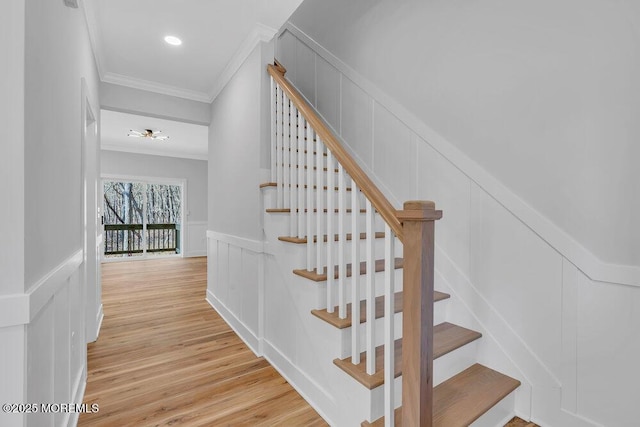 staircase featuring ornamental molding, wood finished floors, and a decorative wall