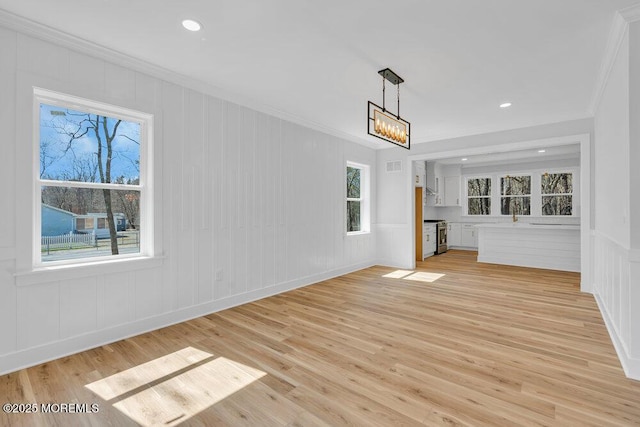 unfurnished living room with light wood-type flooring, visible vents, and crown molding