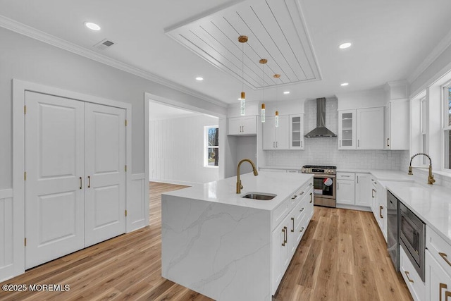 kitchen with crown molding, stainless steel appliances, visible vents, a sink, and wall chimney range hood