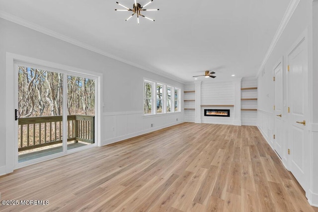 unfurnished living room with light wood finished floors, crown molding, and a glass covered fireplace