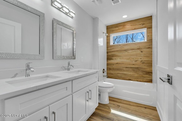 bathroom with toilet, double vanity, a sink, and wood finished floors