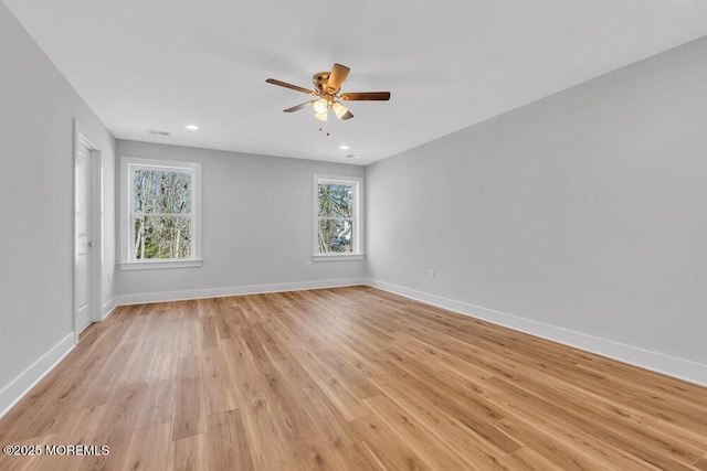 spare room featuring light wood-type flooring, visible vents, ceiling fan, and baseboards