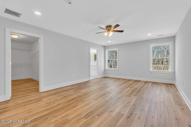 unfurnished room with light wood-style floors, baseboards, visible vents, and a wealth of natural light