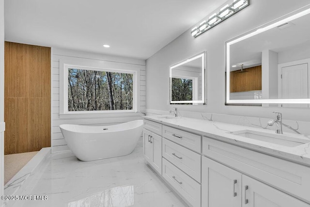 bathroom featuring a soaking tub, marble finish floor, a sink, and double vanity