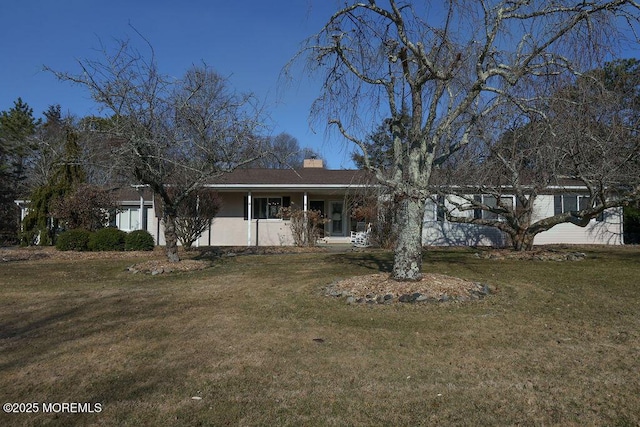 view of front facade with a front lawn, covered porch, and a chimney