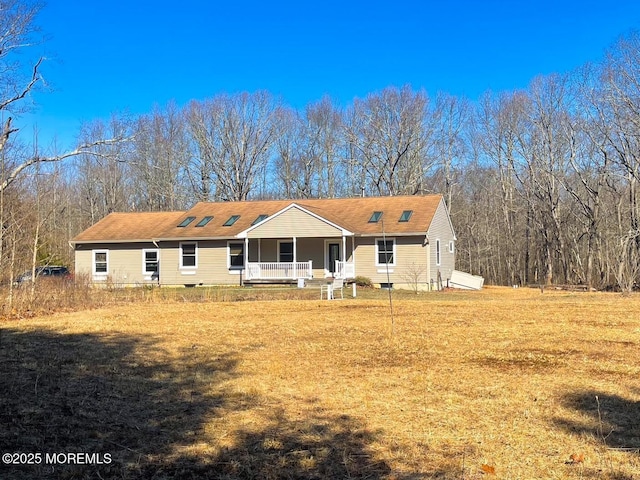 rear view of property featuring a porch, a yard, and crawl space