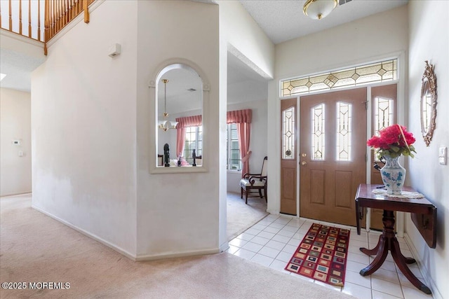 tiled entrance foyer featuring carpet, baseboards, and a high ceiling