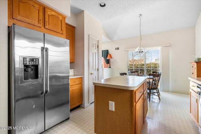 kitchen with stainless steel fridge with ice dispenser, lofted ceiling, brown cabinets, a center island, and light floors