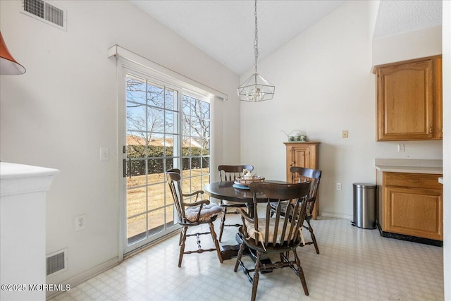 dining room with baseboards, visible vents, vaulted ceiling, and light floors