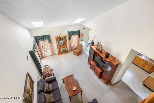 living area with light carpet, lofted ceiling with skylight, visible vents, and a textured ceiling