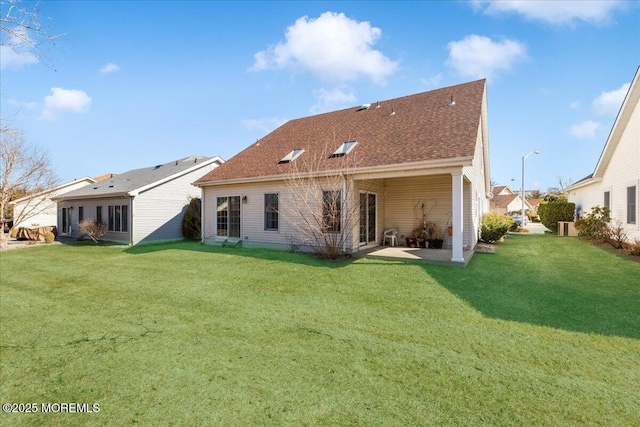 rear view of house featuring a patio area, a lawn, and roof with shingles