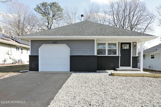 view of front of home with an attached garage, driveway, brick siding, and a shingled roof