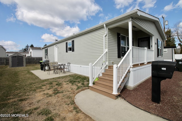 back of house featuring fence, a lawn, a storage shed, an outdoor structure, and a patio