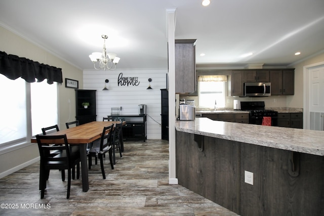 kitchen featuring ornamental molding, stainless steel microwave, a kitchen breakfast bar, light countertops, and black range with gas cooktop