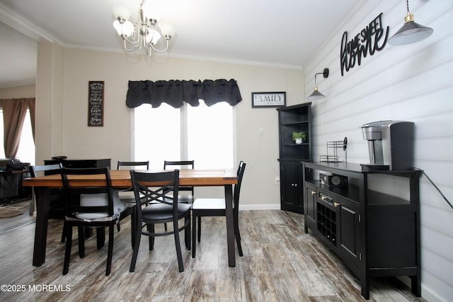 dining area featuring a chandelier, wood finished floors, baseboards, and ornamental molding