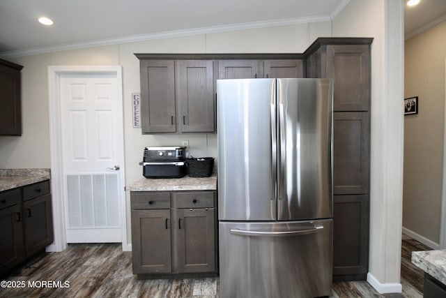 kitchen with baseboards, dark wood finished floors, freestanding refrigerator, ornamental molding, and dark brown cabinetry