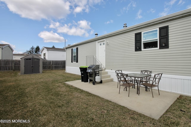 back of property with fence, a shed, a yard, an outdoor structure, and a patio area