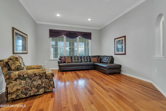 living area featuring arched walkways, light wood-style flooring, crown molding, and baseboards