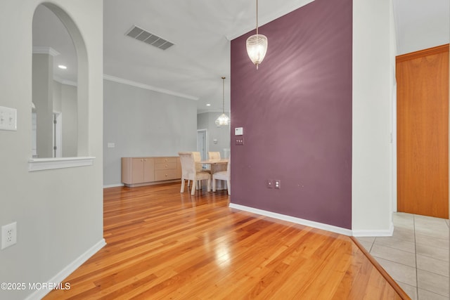 interior space with crown molding, baseboards, visible vents, and light wood finished floors