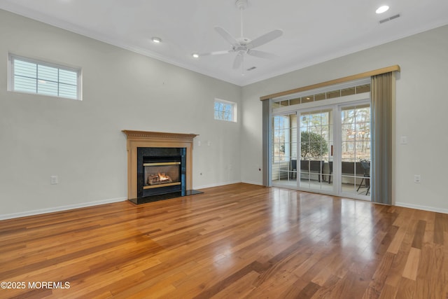 unfurnished living room featuring a glass covered fireplace, crown molding, visible vents, and wood-type flooring