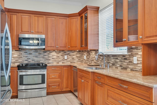 kitchen featuring light stone counters, light tile patterned flooring, a sink, ornamental molding, and stainless steel appliances