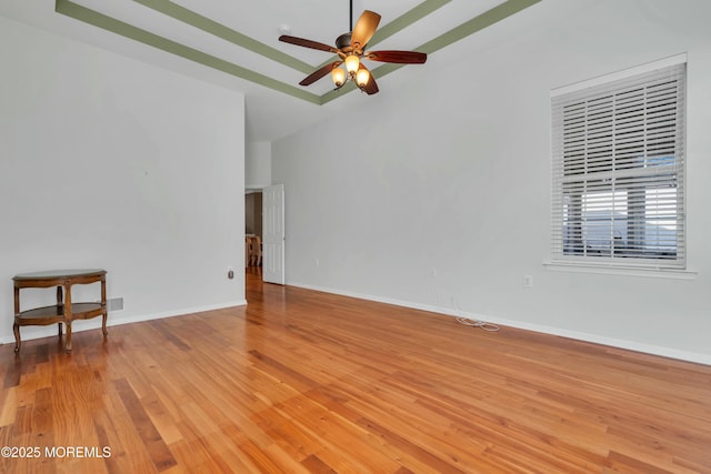 unfurnished room with a ceiling fan, baseboards, light wood-type flooring, and a towering ceiling