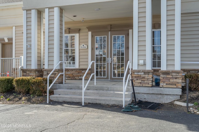 doorway to property featuring a porch, french doors, and stone siding