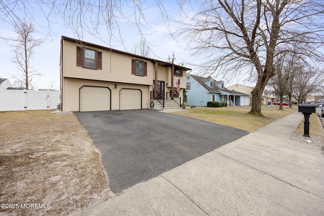 raised ranch featuring driveway, a garage, a residential view, a gate, and fence