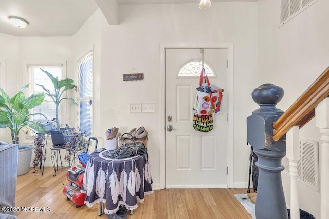 foyer featuring stairway, baseboards, visible vents, and wood finished floors