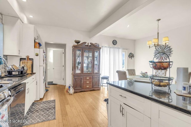 kitchen with dark countertops, light wood-style flooring, black dishwasher, and white cabinetry