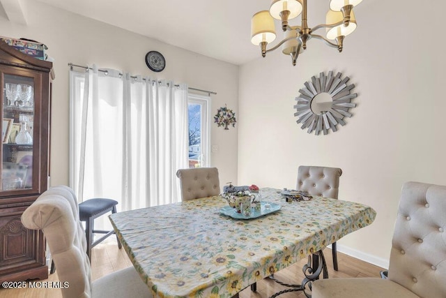 dining space with baseboards, light wood-style flooring, and an inviting chandelier