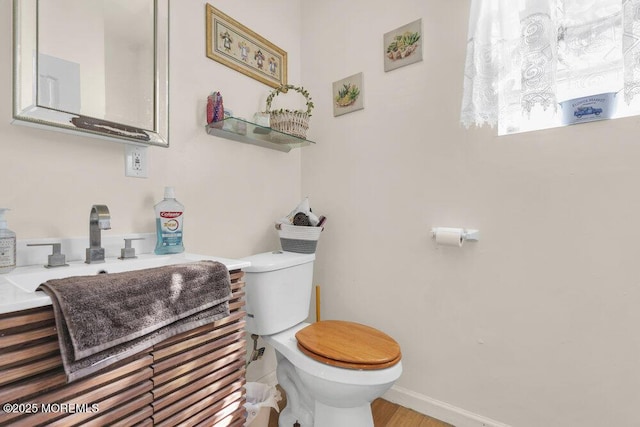 half bath with toilet, baseboards, and vanity