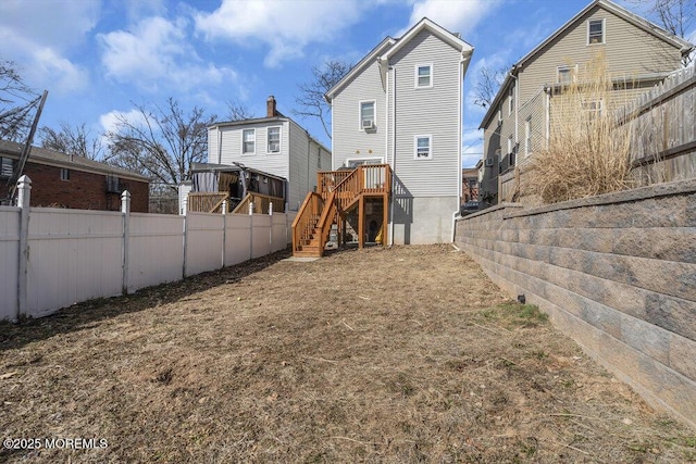 back of property with a fenced backyard and stairway