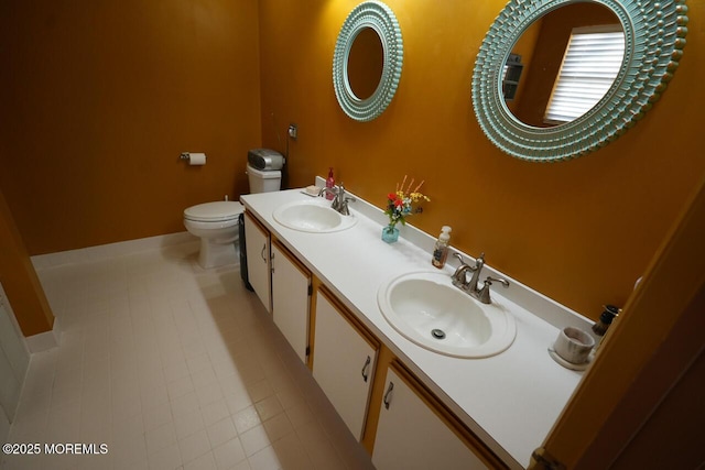 bathroom with double vanity, a sink, toilet, and tile patterned floors