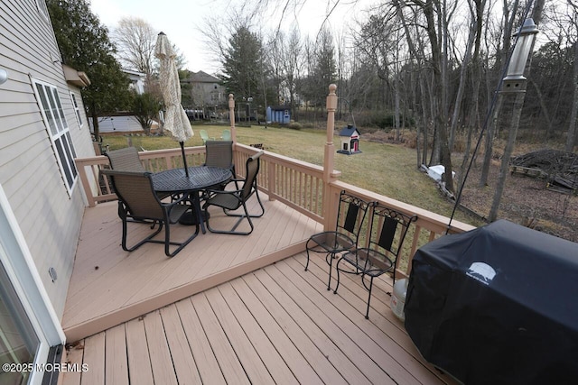 wooden terrace with a yard, outdoor dining area, and area for grilling