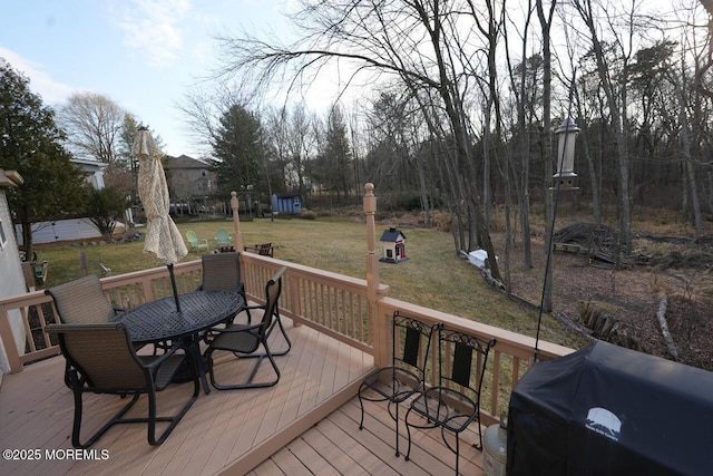 deck featuring a grill, a lawn, and outdoor dining space