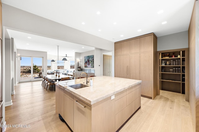 kitchen with light brown cabinetry, light stone countertops, a sink, and modern cabinets