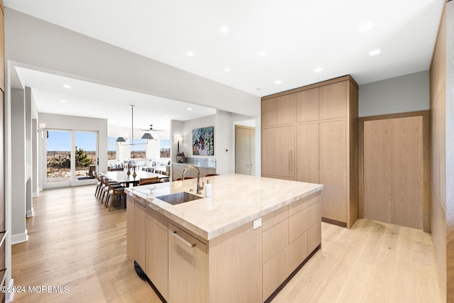 kitchen with light brown cabinets, light stone counters, modern cabinets, and a sink